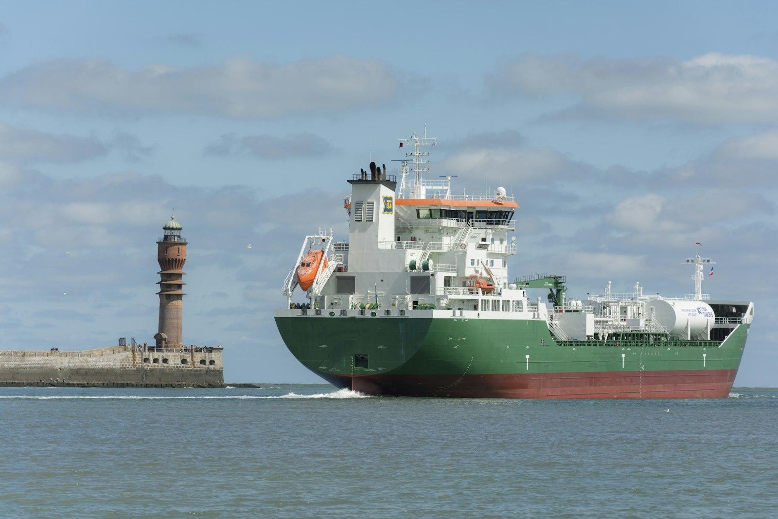 Gas carrier under way past a coastal lighthouse