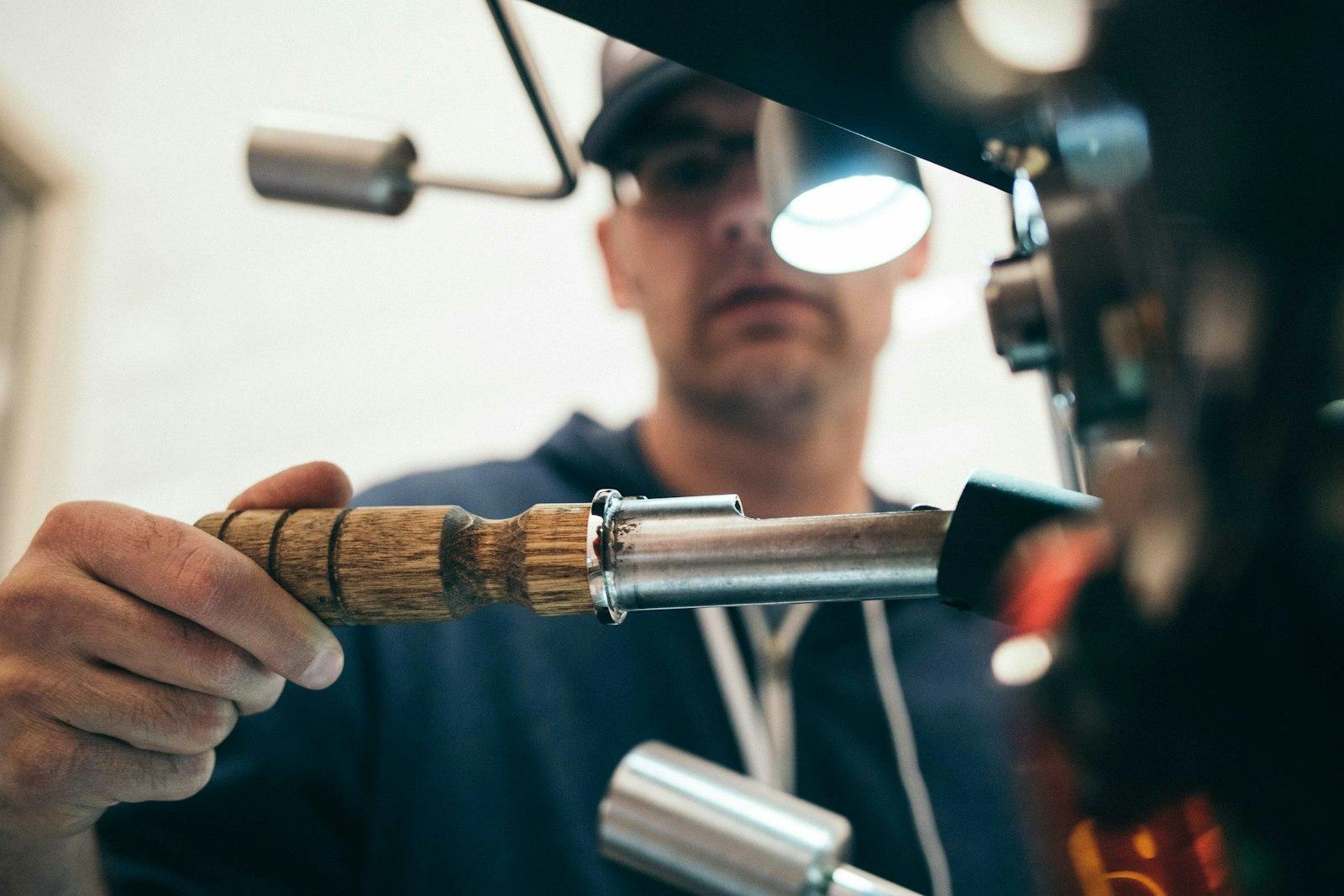 Technician inspecting machinery components under workshop lighting