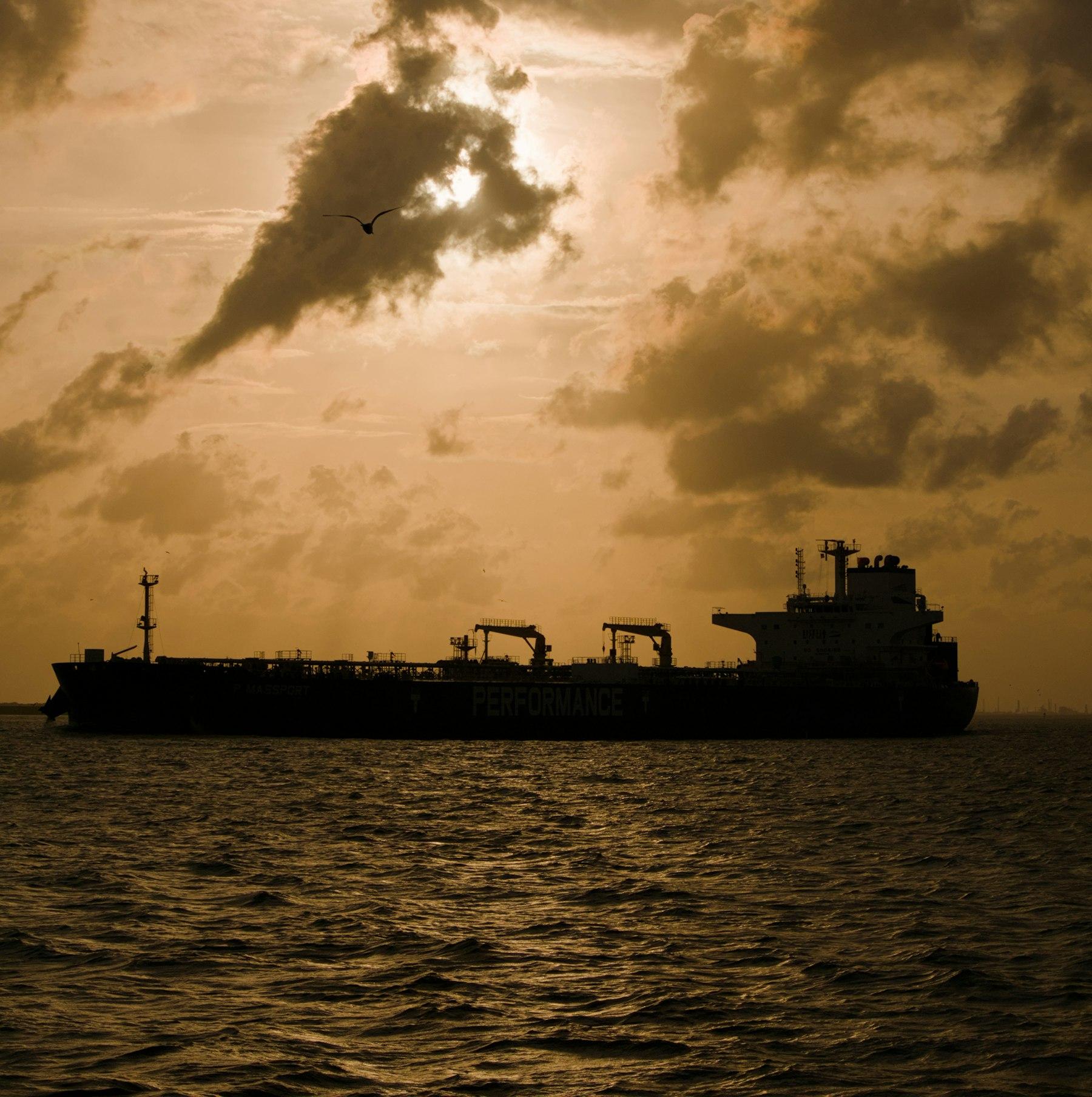 Tanker silhouetted against a golden sunset at sea