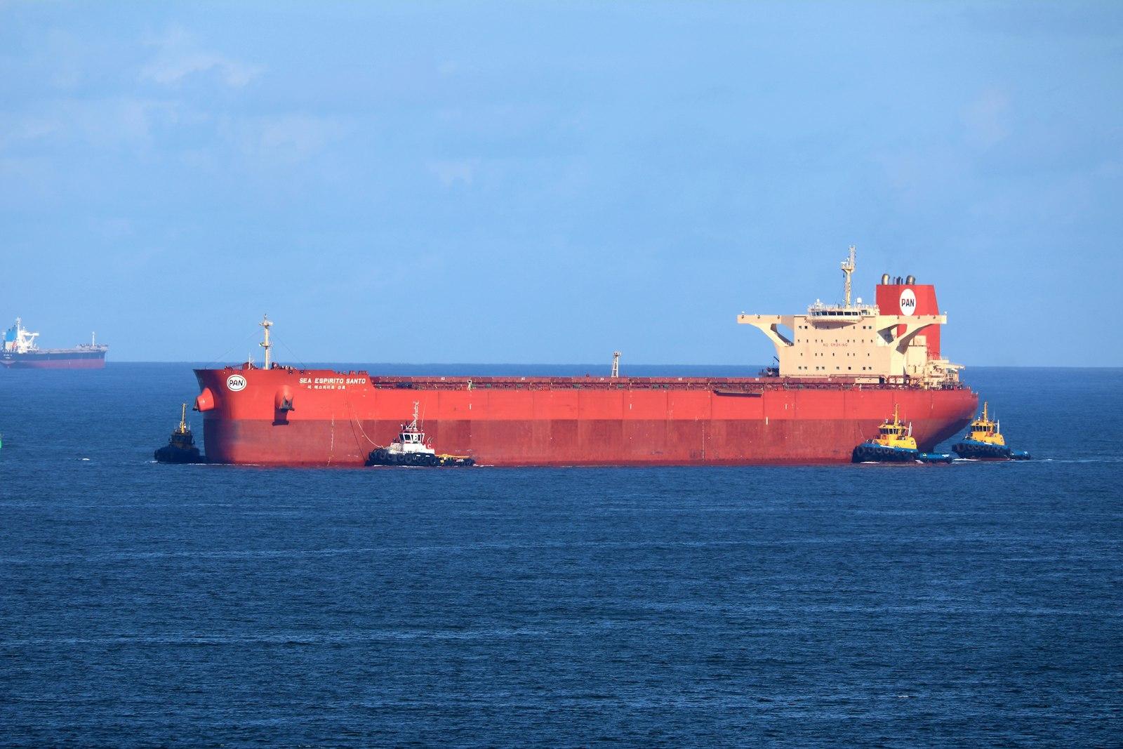 Crude oil tanker attended by tugs off the coast
