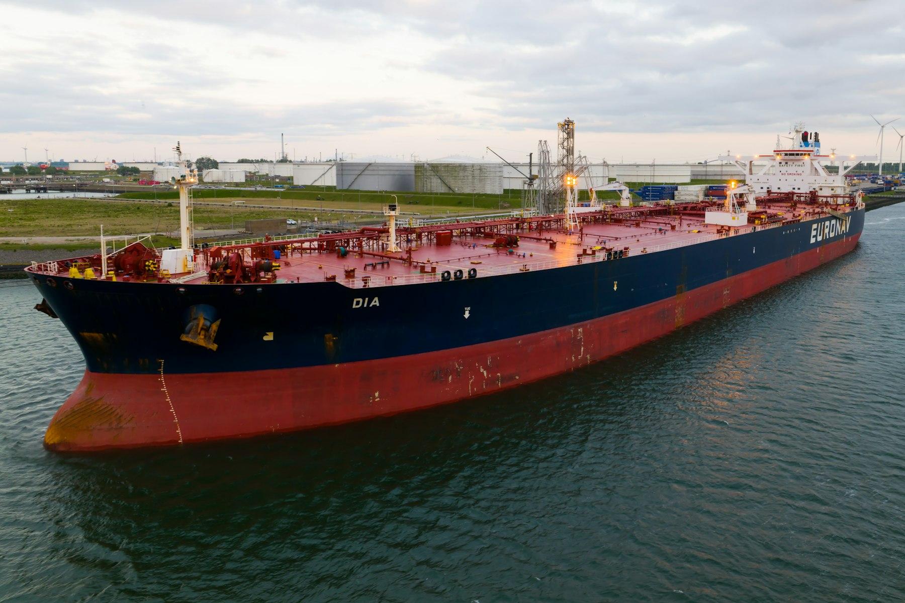 VLCC tanker berthed at an oil terminal with storage tanks behind